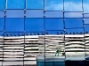 Two workers re-caulking windows on the sixth floor of Van Andel Institute are reflected in the side of the new Helen DeVos Children's Hospital on Monday, August 30 on Michigan Street in Grand Rapids.